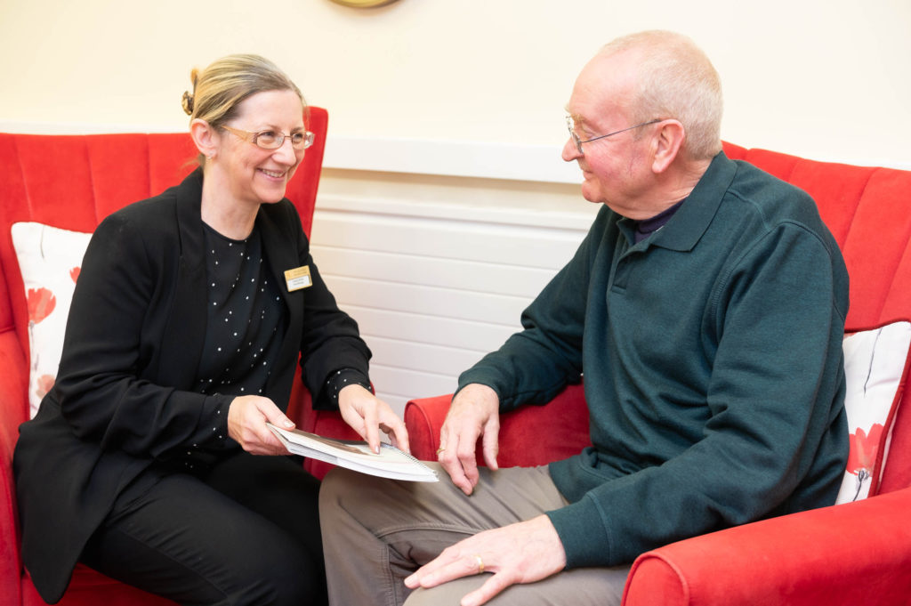 A member of staff going through a booklet with an elderly resident.